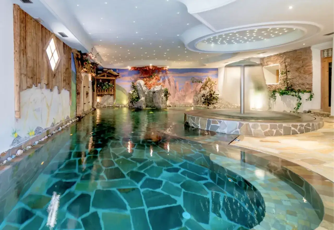 Piscina interna con cascata e decorazioni naturali, un'oasi di relax al Hotel Sporting Andalo.
