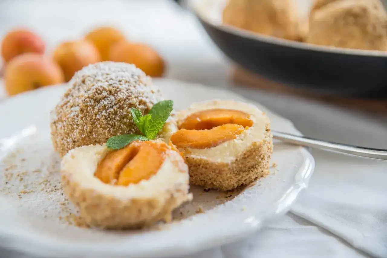 Deliziosi canederli dolci trentini ripieni di albicocche, spolverati di zucchero a velo e guarniti con menta.