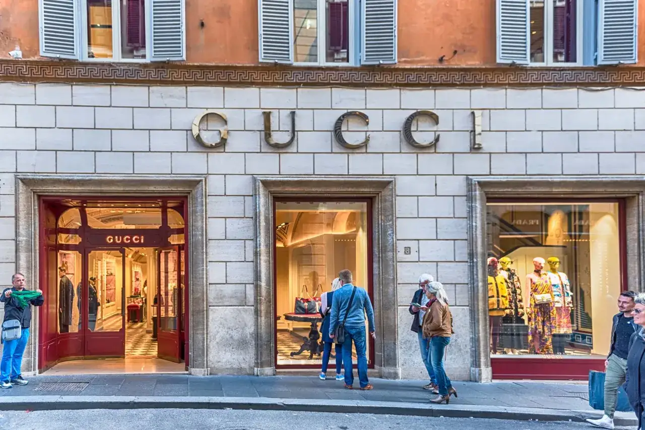 Persone passeggiano davanti alla boutique Gucci, un'icona dello shopping a Roma.
