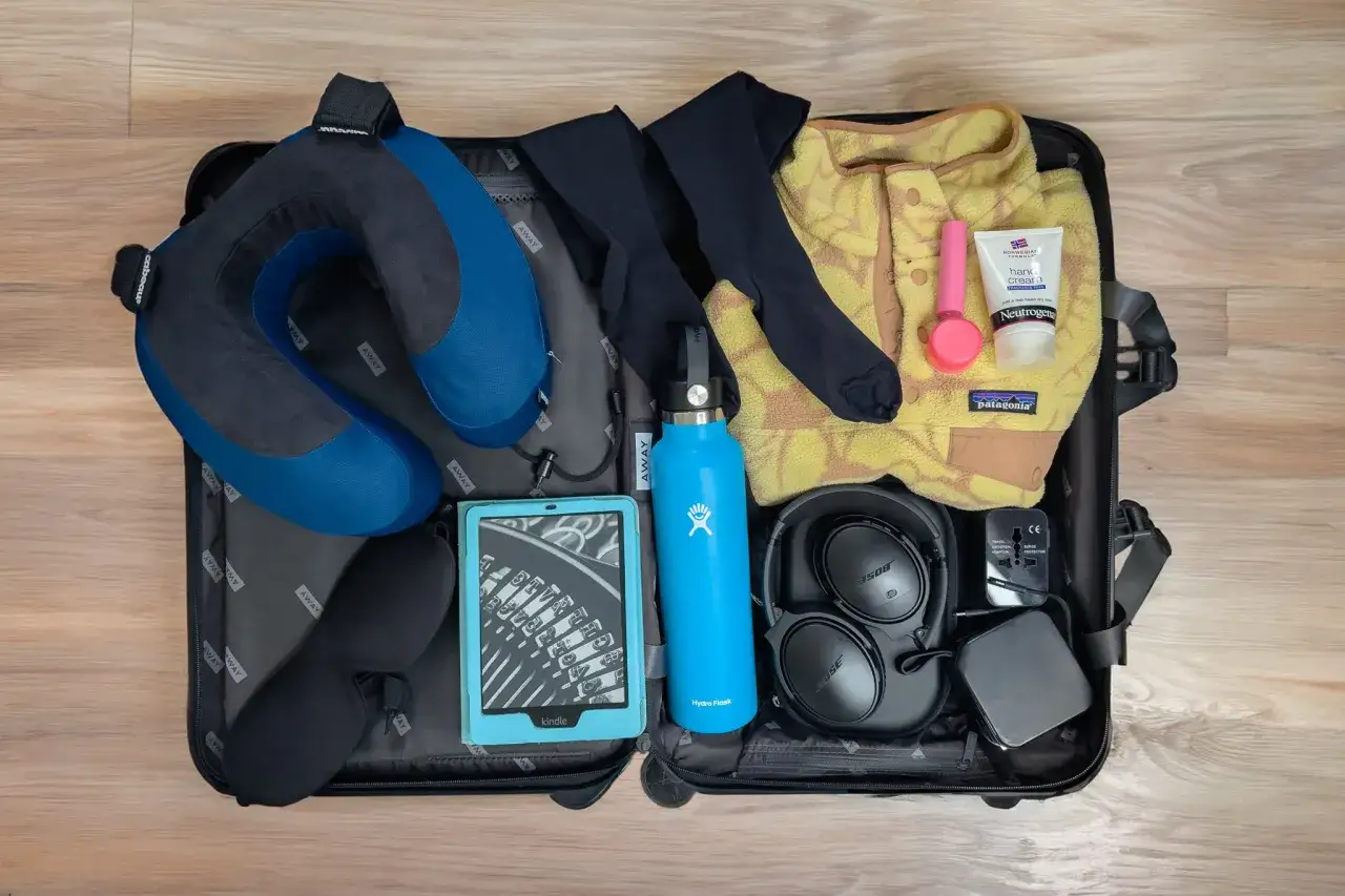 Cuscino da viaggio, maschera per dormire, Kindle, borraccia, cuffie, crema mani e adattatore: ecco cosa si può portare in aereo per un viaggio comodo.