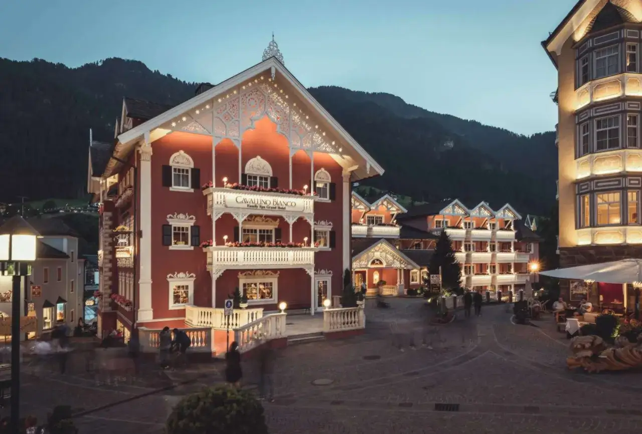 Il Cavallino Bianco Family Spa Grand Hotel, un'oasi di lusso alpino, brilla di luci calde al crepuscolo, invitando a un soggiorno indimenticabile.