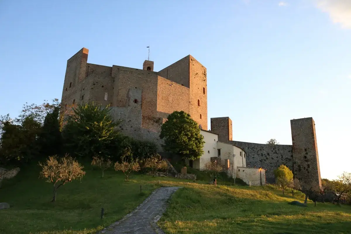 Il castello di Montefiore Conca, imponente e antico, si staglia contro il cielo azzurro al tramonto.