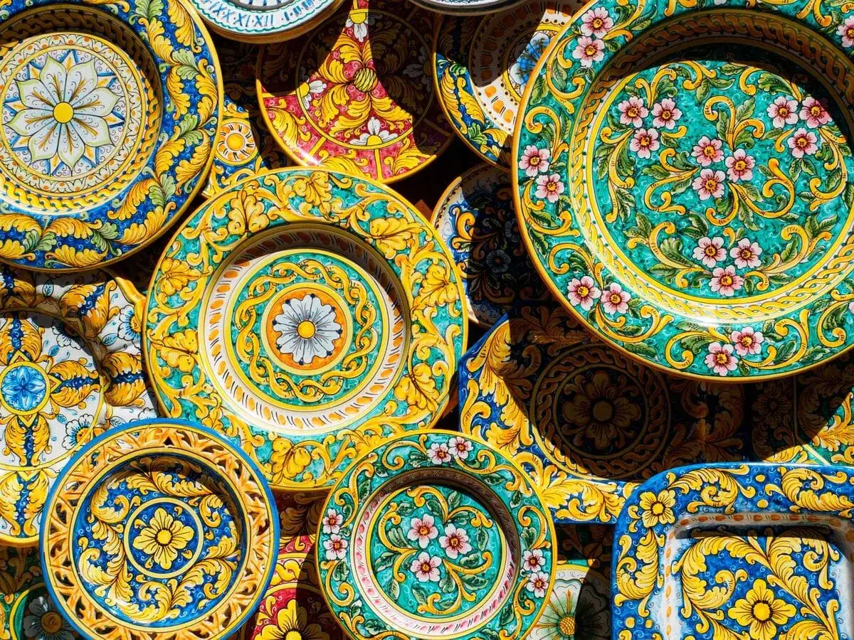 Coloratissimi piatti in ceramica, perfetti come souvenir di viaggio, decorati con motivi floreali e barocchi in giallo, blu e verde.