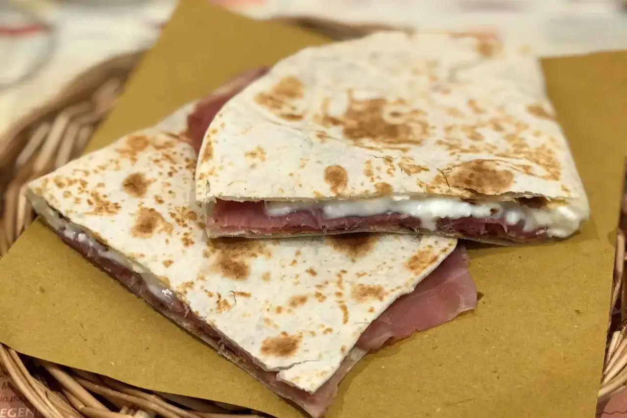 Piadina ricetta: sfogliata e farcita con prosciutto crudo e formaggio cremoso, pronta per essere gustata.