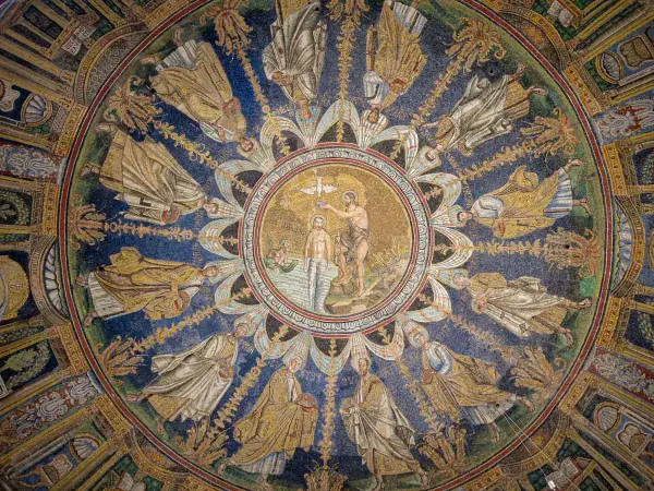 Mosaico circolare con Battesimo di Cristo al centro, circondato da figure di santi e angeli. Un capolavoro da vedere a Ravenna e dintorni.