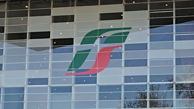 Logo Trenitalia su facciata di vetro. Un'immagine che ricorda il rimborso Trenitalia per ritardi o disservizi.
